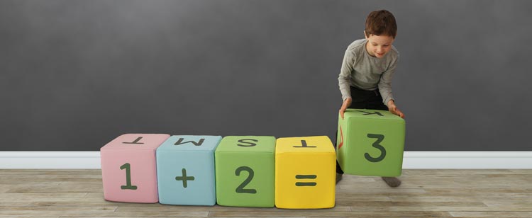 Bogstavklodser som læremiddel til regning. På billedet laver en dreng et regnestykke med klodserne.